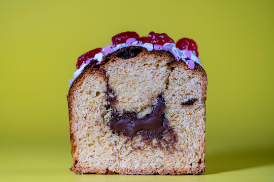 Sliced Easter sweet cake with chocolate filling and cherries on yellow background. Cross section of a sweet bread with melted chocolate inside decorated with icing sprinkles and cherries, closeup