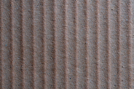 Brown corrugated cardboard texture background. Macro shot of brown corrugated cardboard with vertical ridges. Recycled paper texture for packaging shipping and eco friendly design concepts