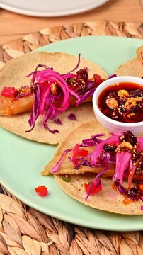 Close-up of gourmet Mexican food with spicy chili oil sauce and peanuts on a rotating plate. Ensenada taco style