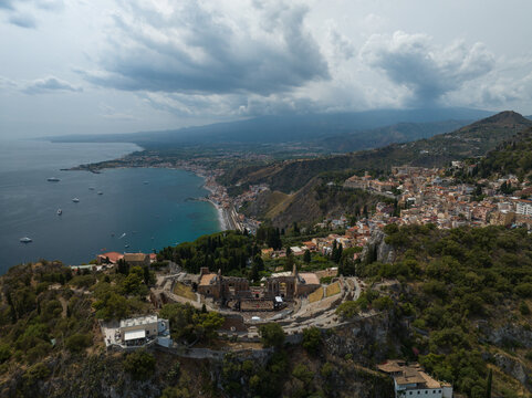 Aerial view of the Ancient Theatre of Taormina overlooking the Ionian Sea and the town under a dramatic cloudy sky Taormina, Sicily, Italy.