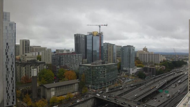 highway time lapTime-lapse view overlooking downtown Seattle, Washington, featuring Interstate 5 traffic flowing through the city's urban core beneath dramatic overcast skies. The scene highlightsse 2
