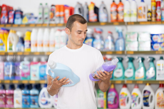 Man examines packaging of bottle with contents, reads information for consumer on label. Compares two different products, get acquainted with assortment and examines different products