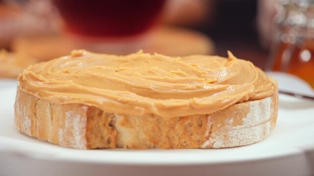 Peanut butter spread on fresh bread slice, homemade breakfast preparation, copy space