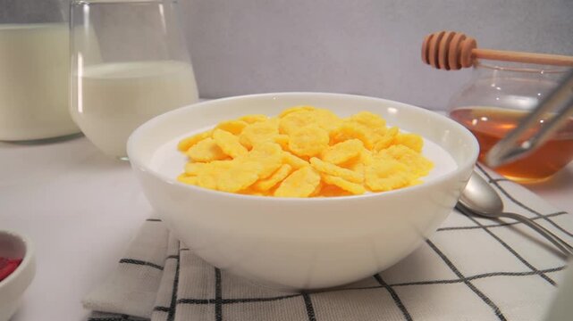 Bowl of corn flakes breakfast on table with glass of milk, fruits and nuts