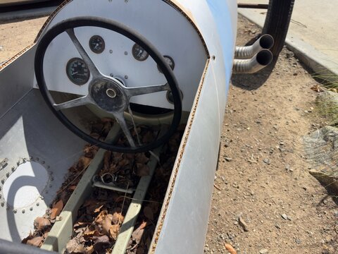 Wide view of a drop tank racer's dashboard, steering wheel, and external motor exhaust pipes.