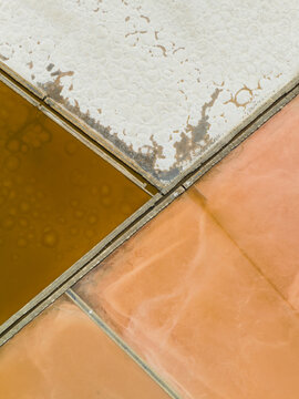 Aerial view of the colorful salt pans with geometric patterns of white salt crusts and tinted water in Marsala, Sicily, Italy.