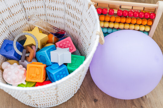 white basket with silicone baby toys abacus and balloon early learning concept