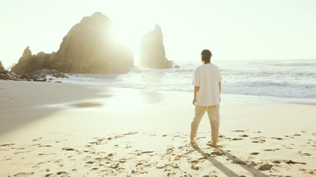 A carefree woman in casual clothing enjoying sunset, walks and splashes in the ocean surf during sunset at "Praia da Ursa" beach, near Sintra, Lisbon, Portugal. Stock slow motion video