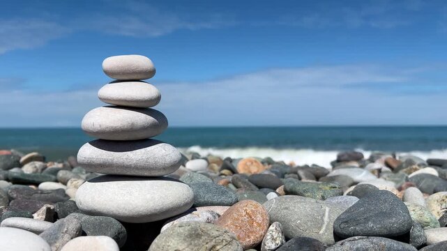 Horizontal 4K video. Small tower, rock pyramid on little stones of pebble beach. Sea shore zen, blue sky, sun, ocean waves, coast. Concept of rest, relax, calm, yoga, self-improvement. Copy space