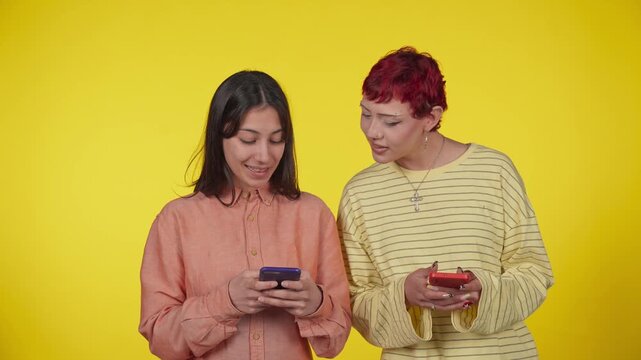 Two female friends using smartphones laughing and gossiping together