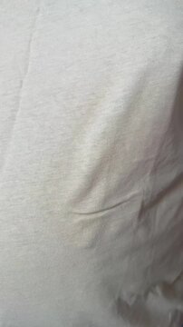 Vertical 4K video close up. 60 fps. Fat adult man in beige T-shirt removes removes 2XL sticker. Concept of Black Friday sale, buying new clothes of extra large size 2 XL, shopping in mall, weight loss