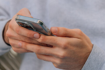 Fototapeta premium Close-up of hands gripping a modern smartphone with a transparent case, showcasing a triple-lens camera system — a sleek blend of technology and everyday human connection