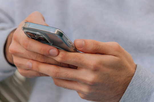 Close-up of hands gripping a modern smartphone with a transparent case, showcasing a triple-lens camera system &mdash; a sleek blend of technology and everyday human connection