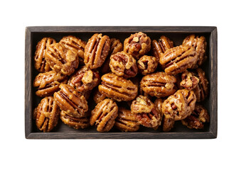 Fototapeta premium Glazed pecan nuts in dark wooden tray, roasted honey pecans with crunchy sugar coating, gourmet candied nut snacks isolated on white background