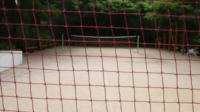 대한민국 서울의 야외 공원 스포츠 경기장 그물망 너머로 보이는 운동장 풍경. 붉은색 네트와 모래 운동장이 어우러진 한국 도심 속 체육 시설 배경.