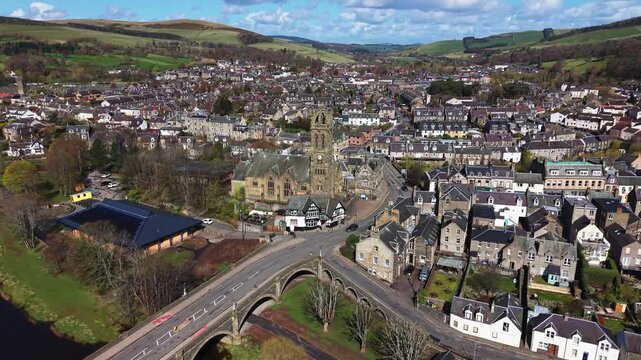 Aerial view of the historic stone Tweed Bridge in Peebles with a traditional church spire and town architecture in the Scottish Borders landscape.