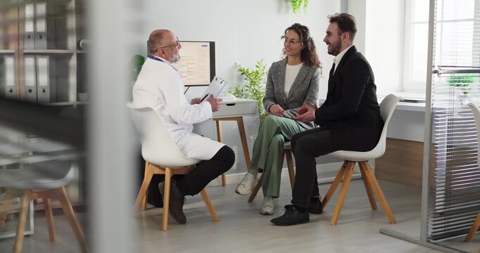 Doctor consults couple in medical clinic office. Supportive consultation answers questions and confirms appointment. Practical advice in healthcare. Clear concept of helpful discussion.
