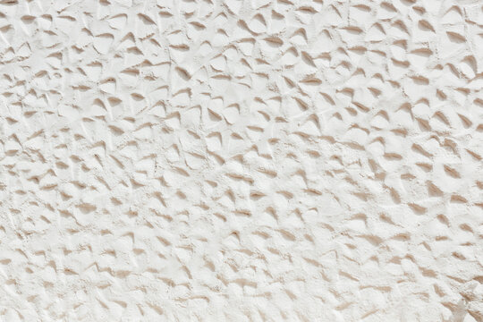 Beautiful view of the street wall with the jagged plaster of a white building.