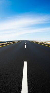 A clean asphalt highway stretches toward the horizon under a clear blue sky, featuring crisp white lane markings and yellow safety lines, path, motorway, transit