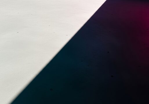 A vast expanse of smooth gray concrete meets a sharp shadow line, creating a stark geometric division ideal for minimalist copy placement, design, wide, minimalism