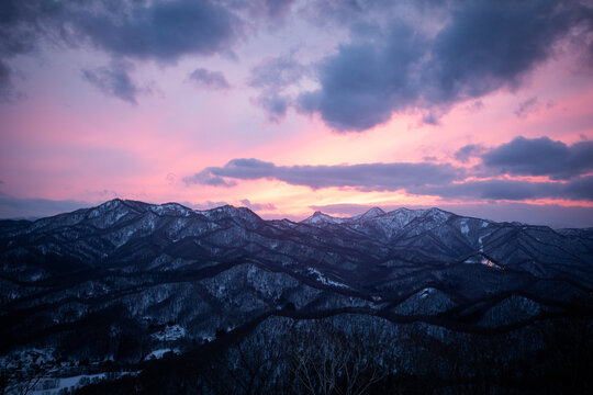 Snowy mountain range under vibrant pink sunset sky