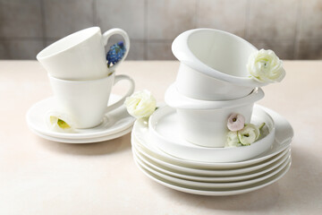 Fototapeta premium Clean dishware and beautiful flowers on light table