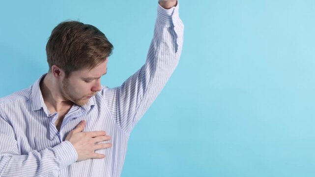 Man with sweaty armpits on light blue background