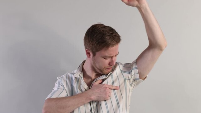 Man suffering from sweating on light background