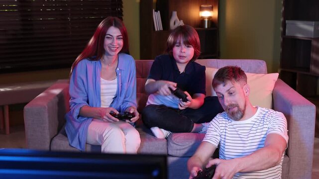 Happy family with controllers playing video game on sofa at home, camera moving right and left