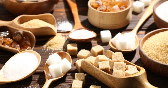 Different types of sugar on wooden table, closeup. Camera moving