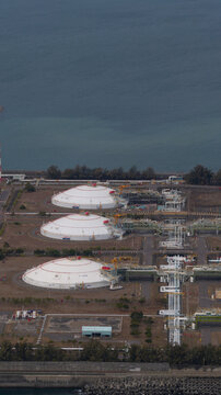 Aerial view of the East Wing LNG receiving station featuring three white storage domes and industrial pipeline infrastructure along the coast in Yong'an District, Kaohsiung City, Taiwan.