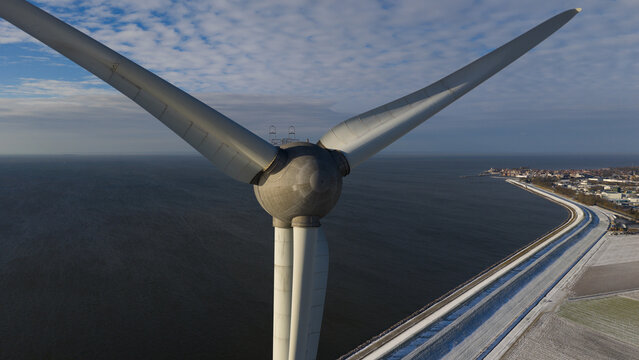 Aerial view of the Westermeerdijk wind turbine hub and blades overlooking the coastline and IJsselmeer sea in Espel, Flevoland, Netherlands.