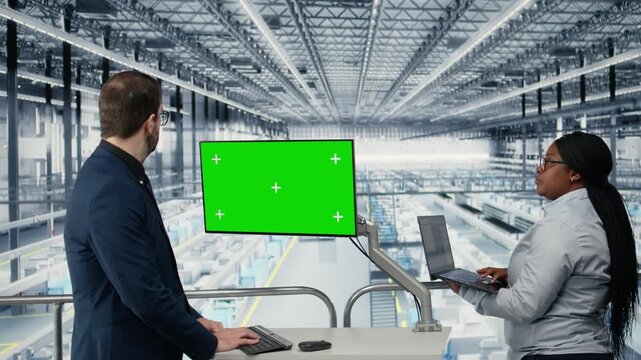 Green screen monitor used by managers reviewing microchip factory diagnostic readouts to prevent downtime. Colleagues study semiconductor plant data on mockup display, doing quality control, camera A
