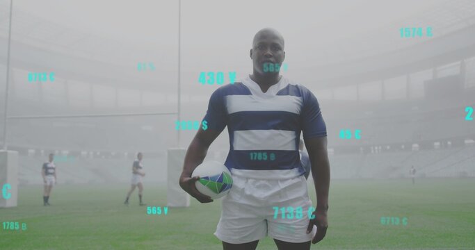 Standing rugby player wearing navy kit holding rugby ball on misty stadium pitch with teal overlays