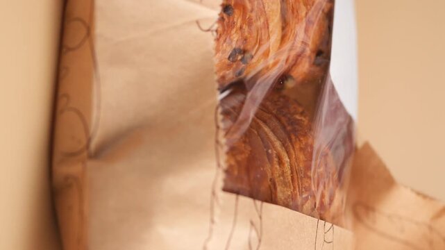 Freshly baked homemade chocolate puff pastry bread loaf in brown paper bag closeup view.