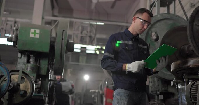 Factory technicians inspect heavy industrial machinery with flashlight, checklist, and manual controls inside a legacy metal workshop, showing maintenance, safety, and skilled diagnostics.
