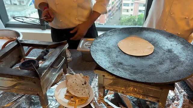 A skilled Indian chef preparing fresh, handmade rotis at a live cooking station during a grand festive event in India.