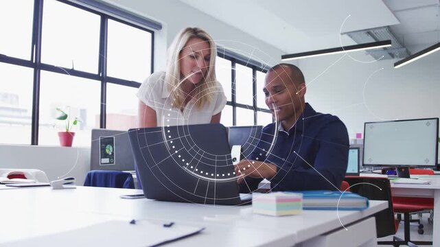 Man typing and woman leaning over laptop in office, HUD overlay highlighting data for report review