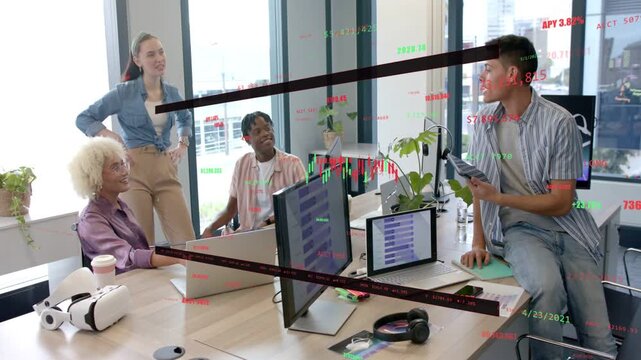 Analyst tapping tablet guiding team at table, animated finance charts over monitors guiding action