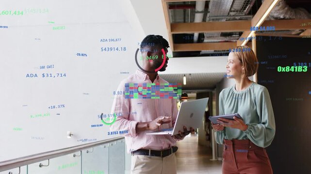 Discussing pair using laptop tablet in office hallway by glass railing with overlays, in pink shirt