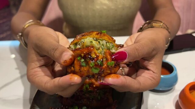 Breaking a fresh Schezwan momo; a lifestyle shot showing the internal stuffing of a popular Indian street food snack in a contemporary Kolkata cafe.