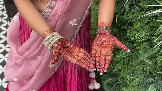 Indian girl in pink dress showing Mehendi design; a colorful lifestyle portrait featuring traditional henna body art and ethnic South Asian fashion.