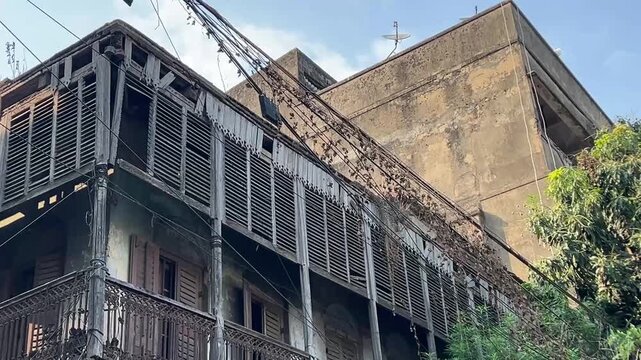 Old building with a beautiful traditional balcony in Kolkata; a historic heritage structure in a state of decay, illustrating the unique urban landscape of West Bengal, India.
