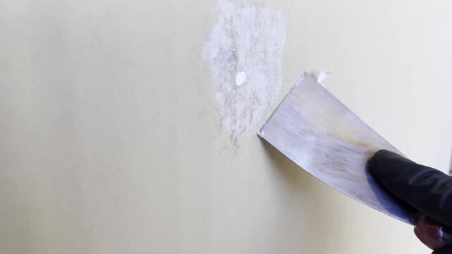 Applying spackle to a small wall hole during interior repair, close up, renovation work. 