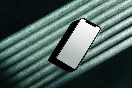Sleek smartphone with blank screen casts shadow on textured surface