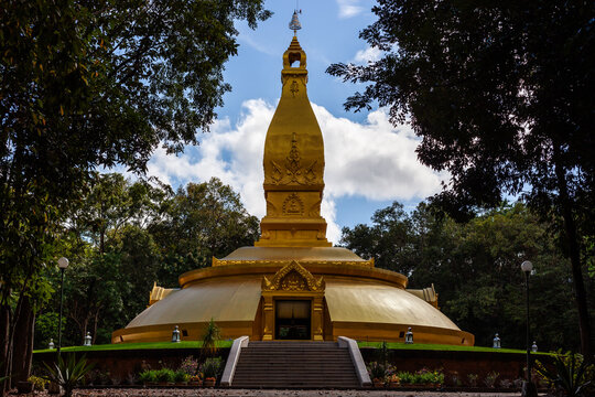 Golden Stupa at Wat Nong Pah Pong in Ubon Ratchathani, Thailand. Surrounded by lush greenery and trees.