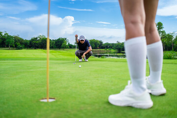 Obraz premium Asian man and woman golfers swing clubs together on scenic golf course. 