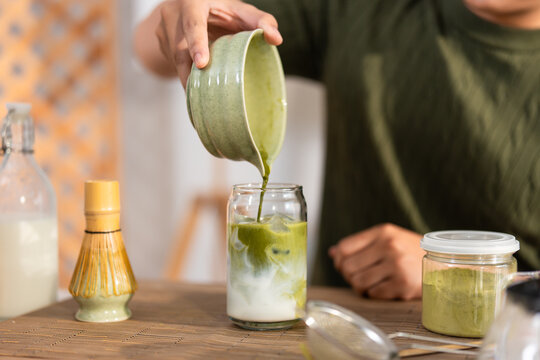 Close up of young man preparing traditional matcha tea in a bowl at home.