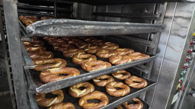 Rows of freshly baked simit displayed on cooling racks in a professional bakery.