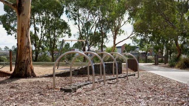 A stainless steel hoop bike rack installed on woodchip ground surface in a local suburban neighbourhood park and playground in Melbourne Australia.&nbsp;Mature eucalyptus gum trees in the background.